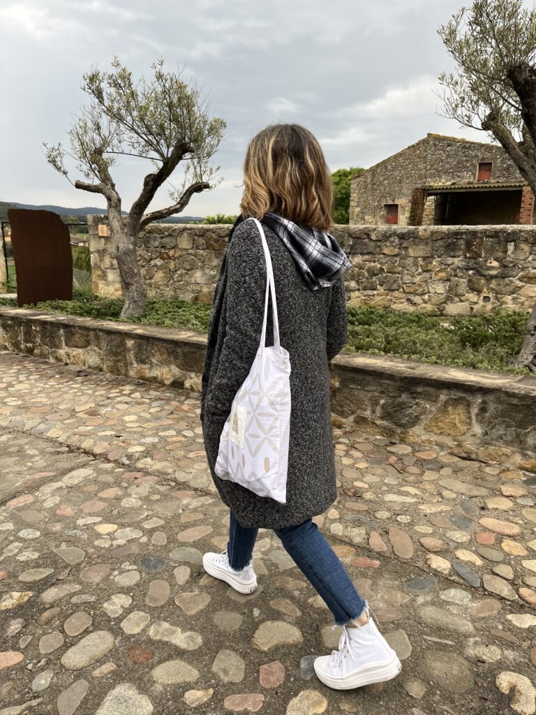 Mujer paseando por un pueblo con una bolsa de tela colgada del hombro